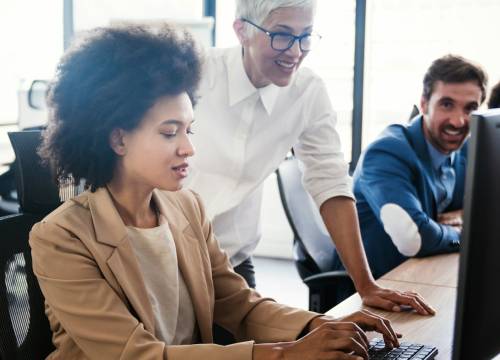 Three colleagues collaborating at a computer in an office.
